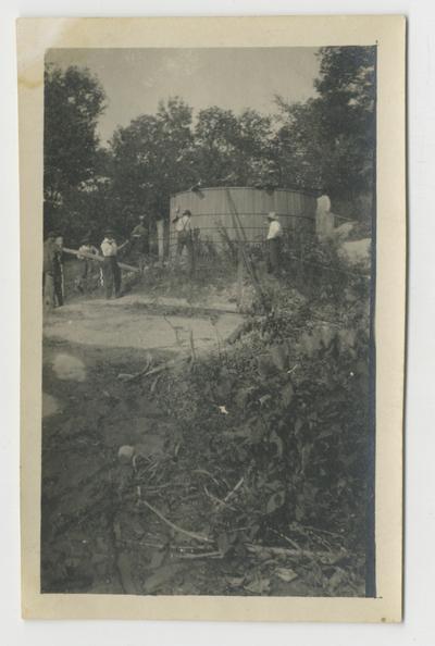 Unidentified persons working around a large above-ground vat