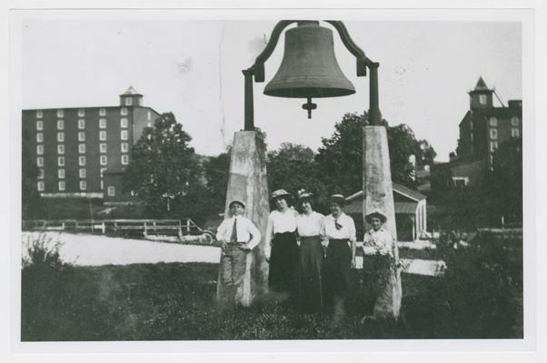 Five children under bell near warehouses