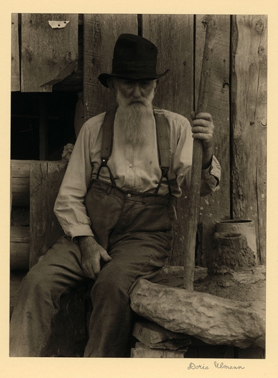 John Menders; Father of Cheevars; Cleveland, Georgia.  Elderly, bearded man in hat and suspenders, seated with big stick