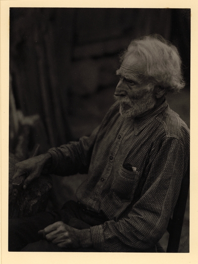 Nick Barton, Civil War veteran, d. May 1928. Profile of elderly, bearded man in polka-dot shirt, seated in chair, holding hatchet