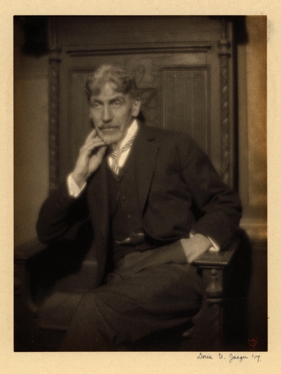 Charles R. Lamb;  Bearded man with mustache, in suit and striped tie, seated in large chair with one hand in pocket and chin resting on other hand