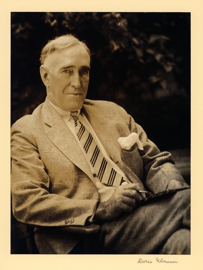 Frank McVey,  President UK; Man in tie and suit with handkerchief, seated outside in chair, holding paintbrush or pen