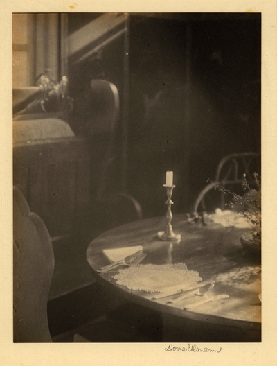 Table with place setting, candlestick, and plant, with window in background