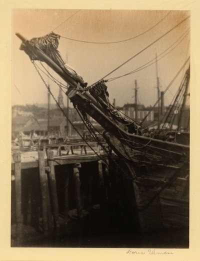 Front of ship with carvings beside wharf at low tide with town in background