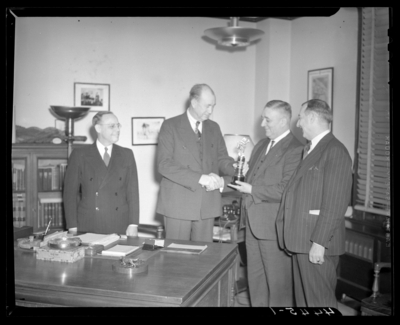 Kentucky Utilities Company (167 West Main Street); interior of                             office, group of men gathered around a desk, man is receiving a trophy                             and accepting congratulatory handshake