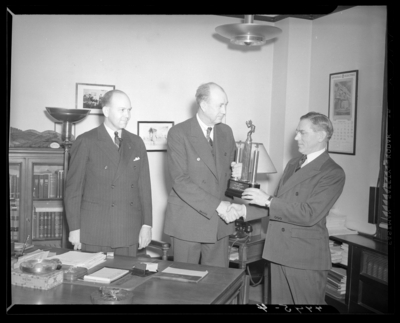 Kentucky Utilities Company (167 West Main Street); interior of                             office, group of men gathered around a desk, man is receiving a trophy                             and accepting congratulatory handshake