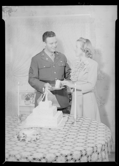 George Ault Jr. & wife; holding piece of cake                             together