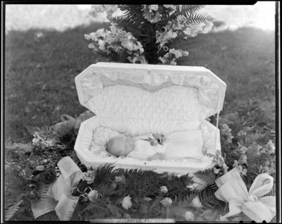 Joe Kines Jr.; corpse (baby); open casket surrounded by                             flowers