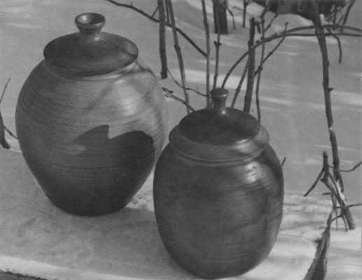 Two ceramic pots with lids sitting in snow, pieces of John Tuska's Alfred University graduate work