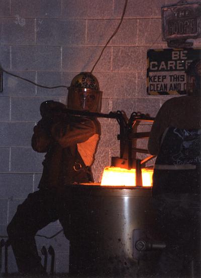 Andrew Marsh and Scott Oberlink lifting a crucible out of the furnace in the University of Kentucky foundry for the casting 