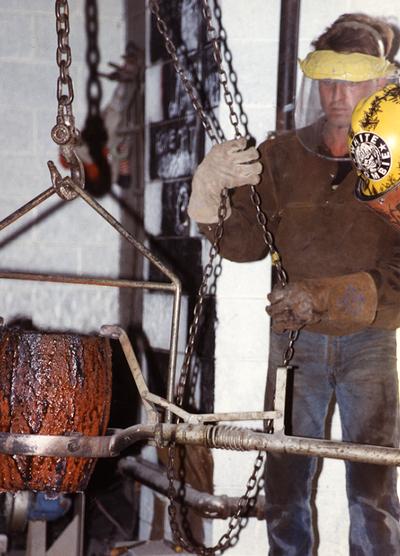 An unidentified man helping to lift a crucible in the University of Kentucky foundry for the casting 