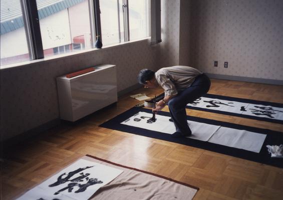 An image a Japanese man named Ishimori-san, painting on a floor. John Tuska visited Japan for the Kentucky Arts Council