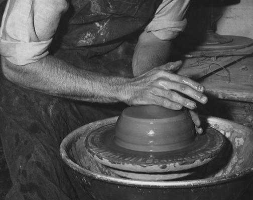 An image John Tuska throwing clay on a potter's wheel for a pot