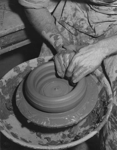 An image John Tuska shaping a clay pot on a potter's wheel