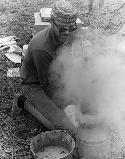 John Tuska cooling a clay vessel after a raku firing