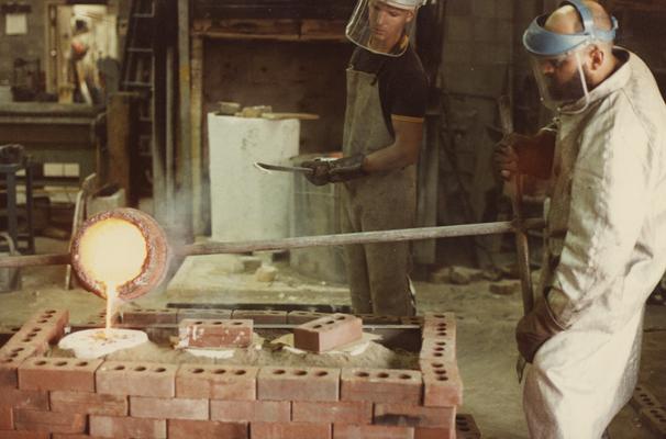 An unidentified person and Jack Gron pouring for a cast at the University of Kentucky foundry. The photograph was taken by Ted Bronda